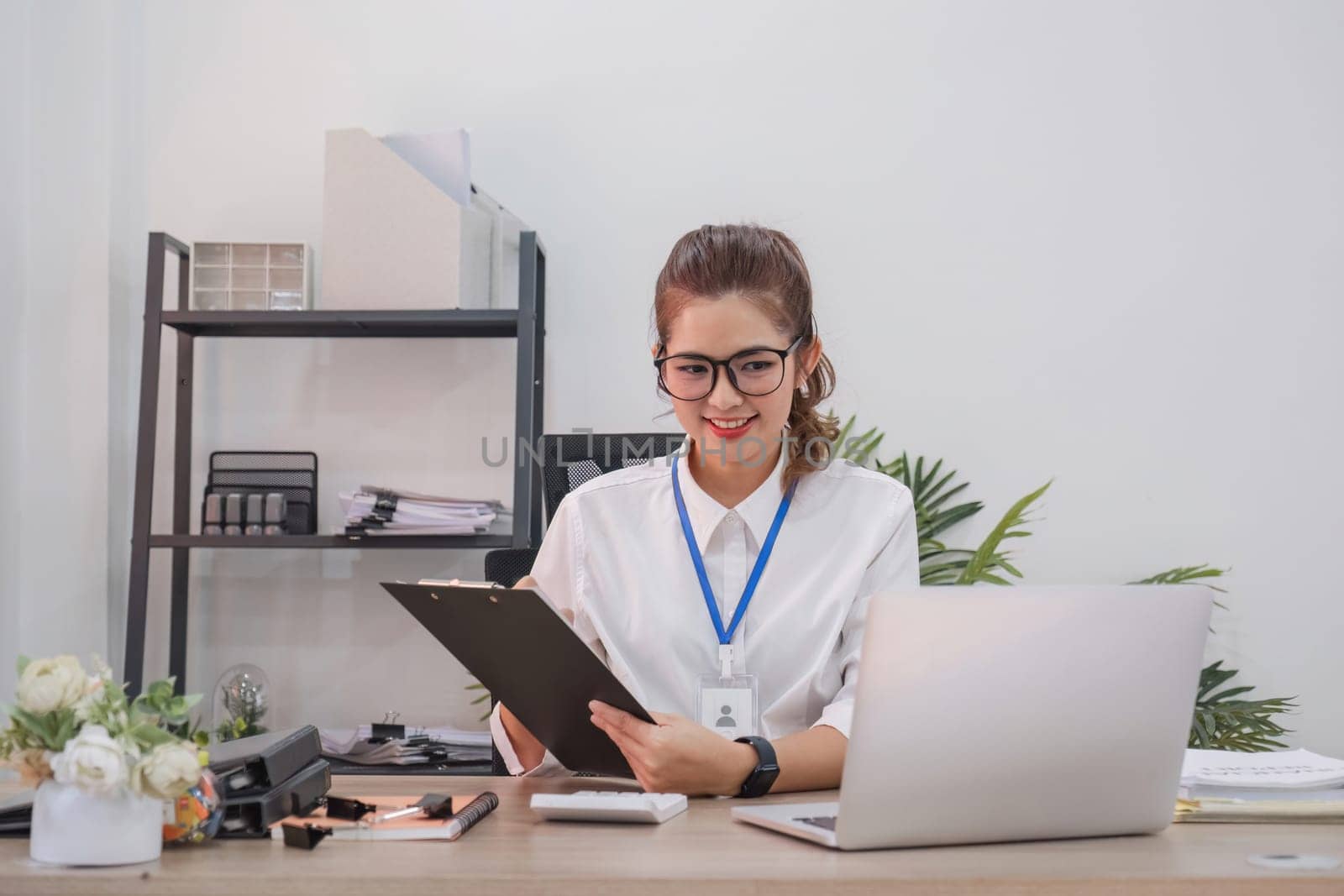 Businesswoman is doing a video conference and showing charts on a clipboard while working at home. by wichayada