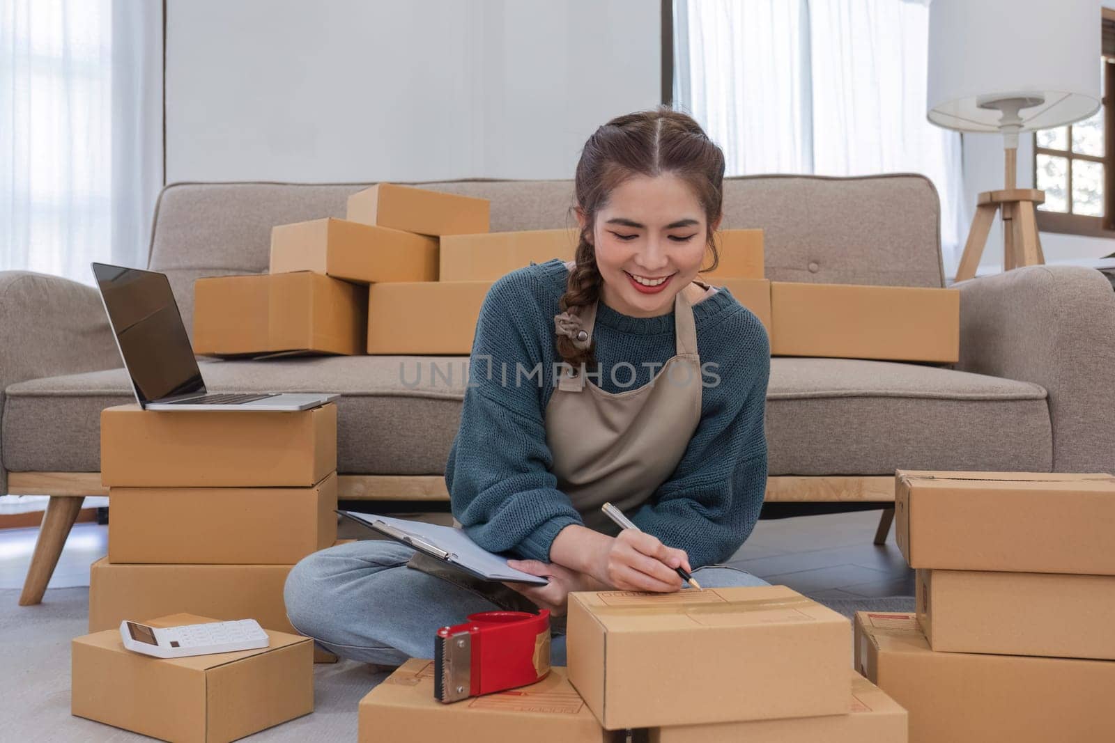 Startup small business entrepreneur SME, asian woman packing cloth in box. Portrait young Asian small business owner home office, online sell marketing delivery, SME e-commerce telemarketing concept by wichayada