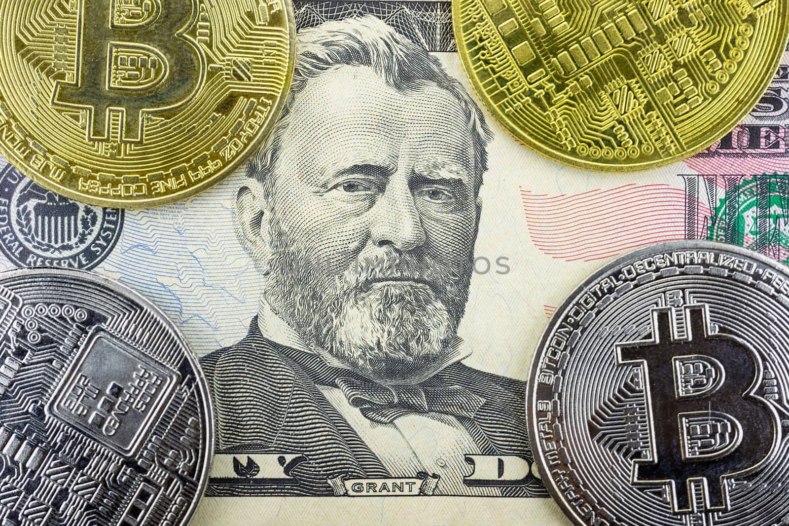 Bitcoin coins lie on a fifty dollar bill, close-up