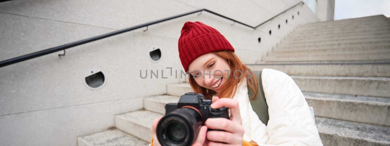 Portrait of female photographer walking around city with professional camera, taking pictures capturing urban shots, photographing outdoors.