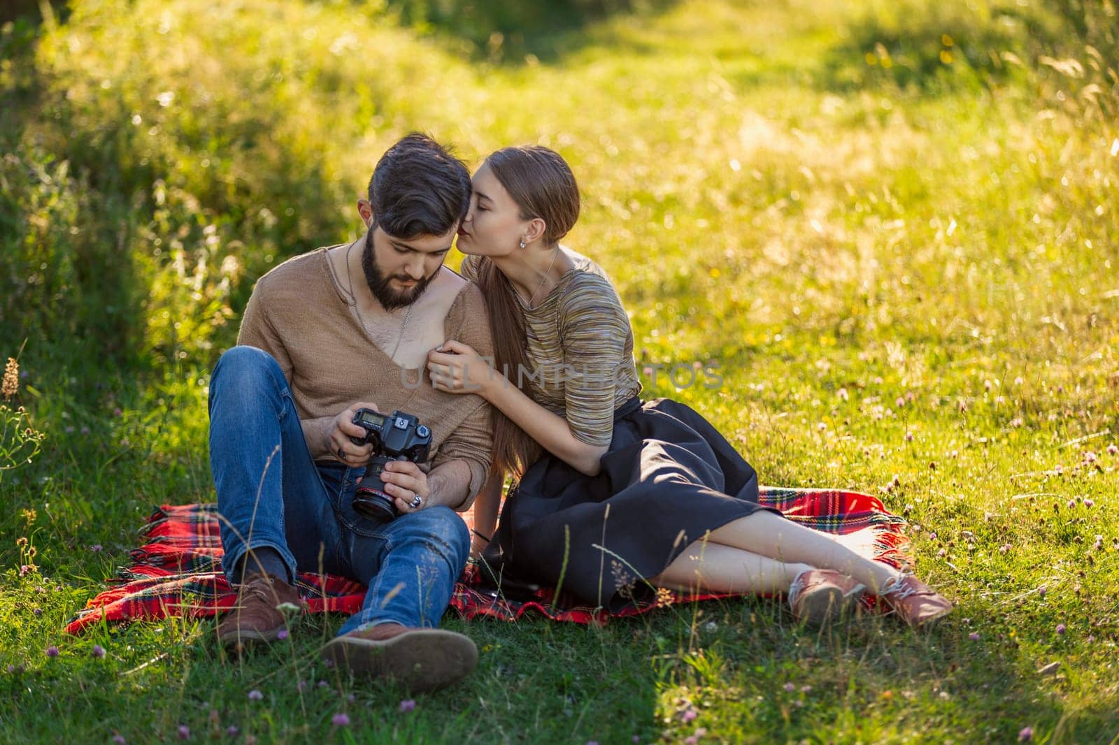 young couple relaxing in nature and looking at photos on a camera