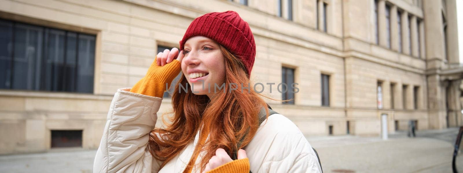 Tourism and travelling. Young redhead woman smiling, tourist walking with backpack around city centre, sightseeing, holds backpack with paper map by Benzoix