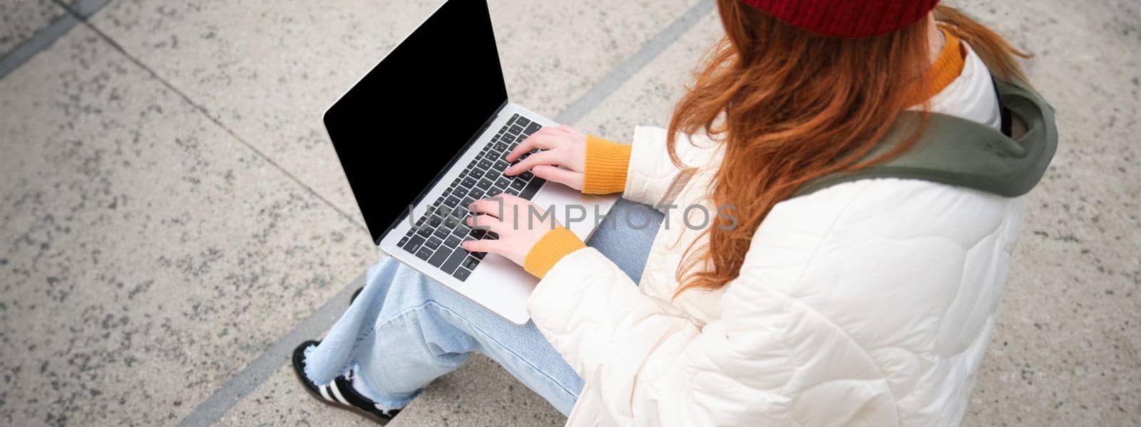 Rear view of girl student typing on laptop keyboard, blank black screen for website application advertisement, sitting on stairs outdoors, connects to public wifi by Benzoix