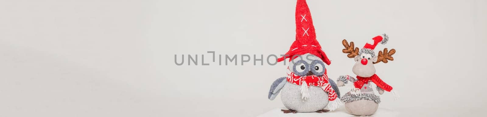 A toy figure of an owl and deer in a red hat. Isolated on a grey background. christmas decorations