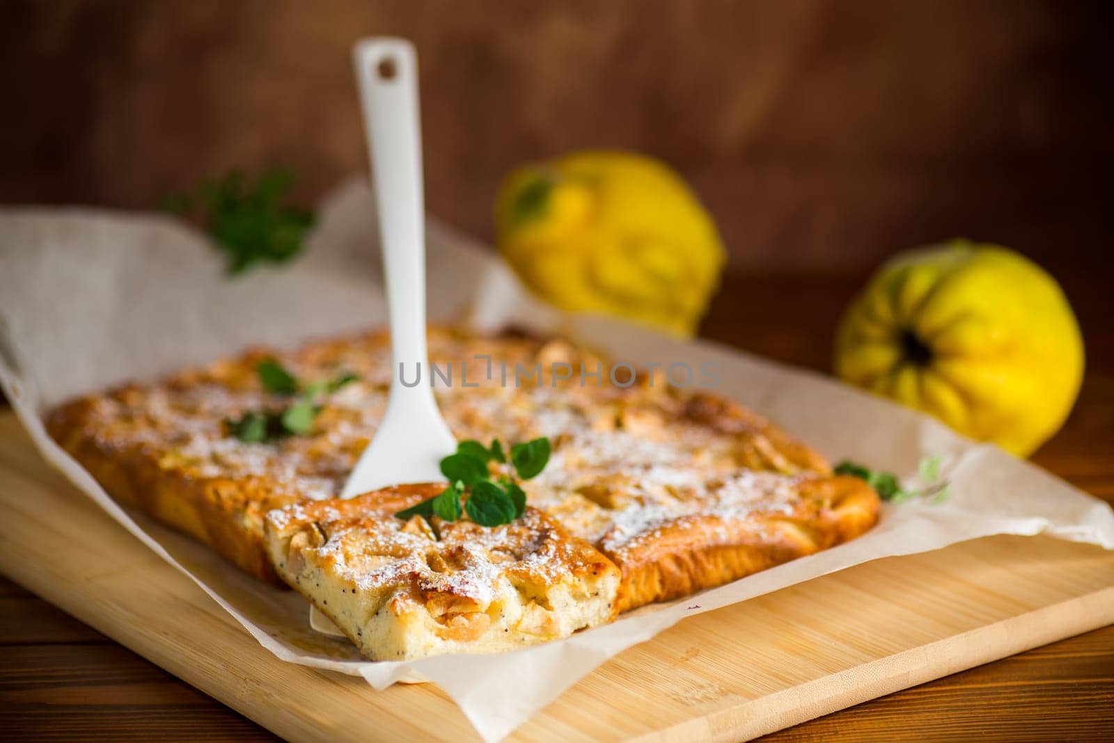 prepared curd semolina pie with quince inside and covered with powdered sugar on a wooden board.