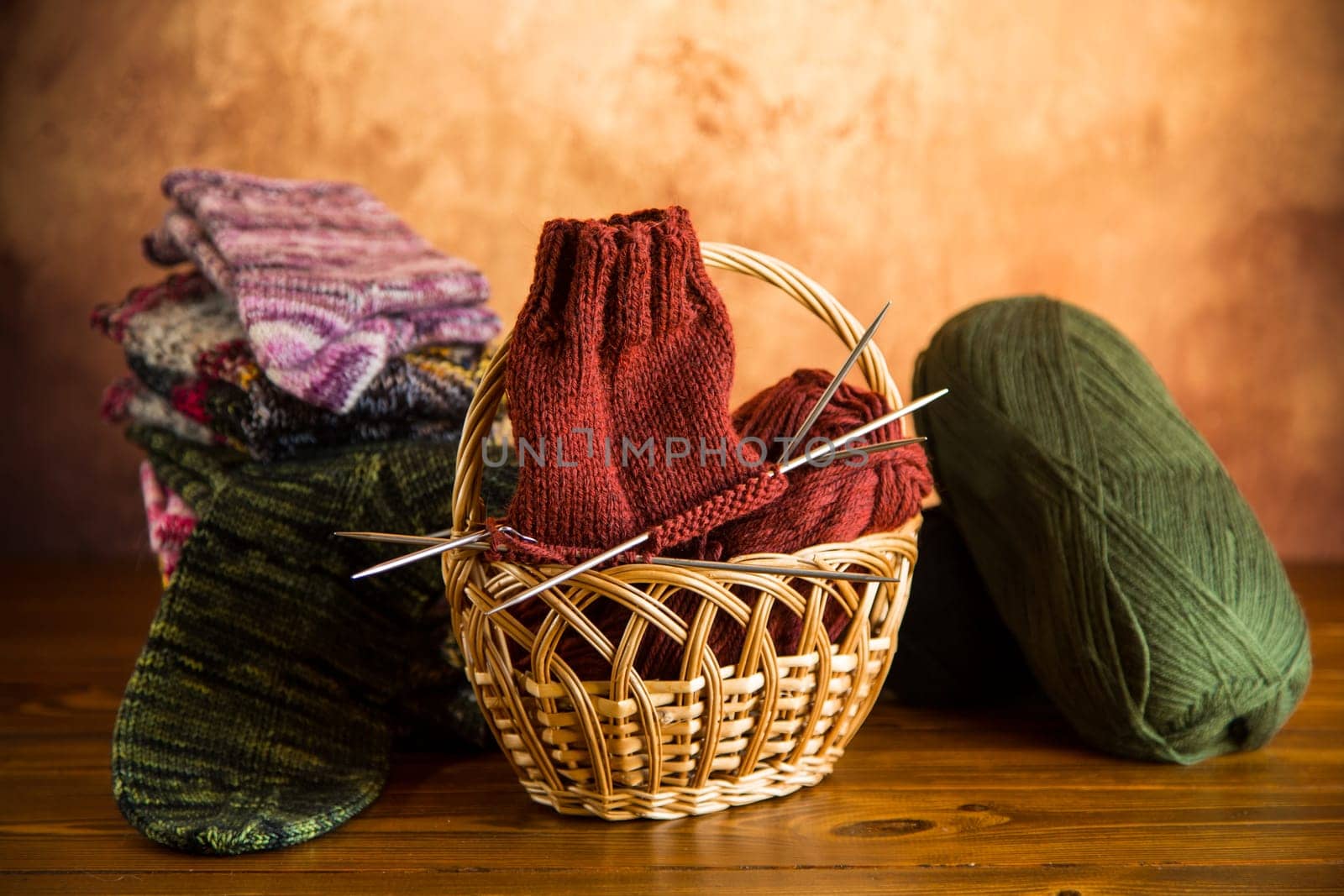 Colored yarn, knitting needles and other items for hand knitting on a dark wooden table.
