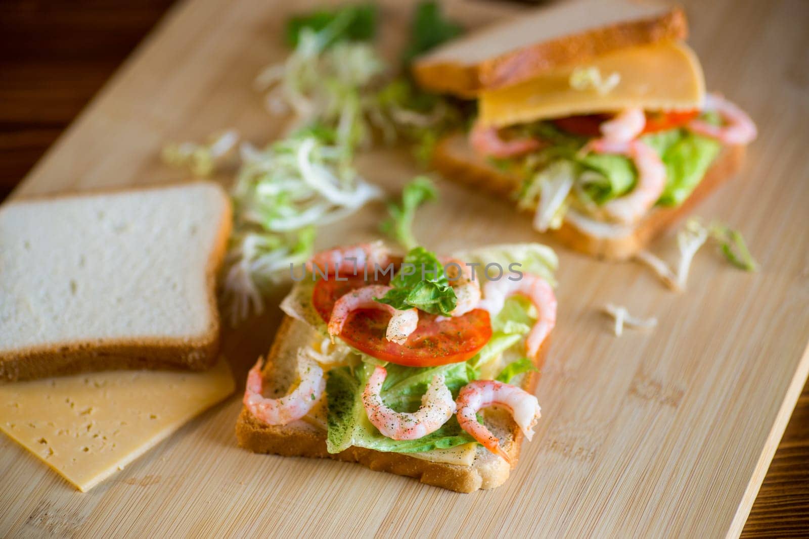 sandwich with lettuce and shrimp on a wooden board