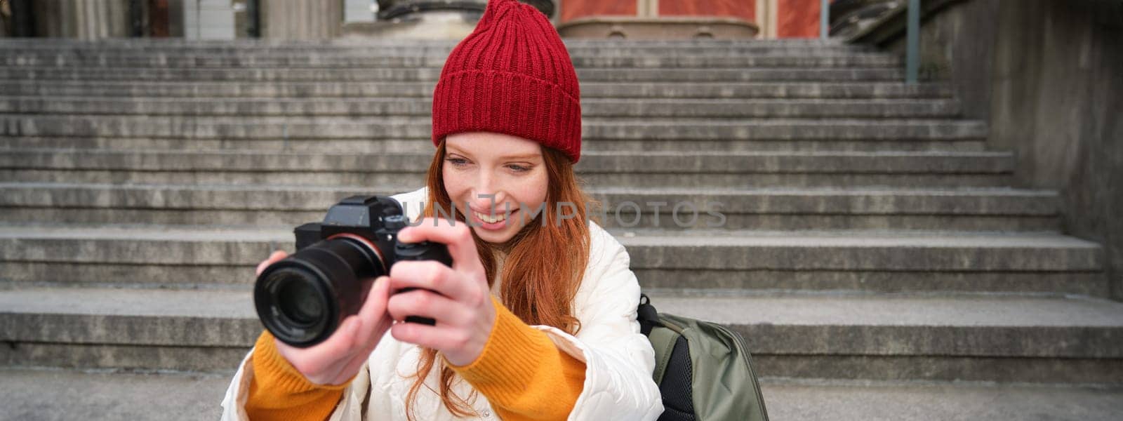 Portrait of young photographer girl, sits on stairs with professional camera, takes photos outdoors, making lifestyle shooting by Benzoix