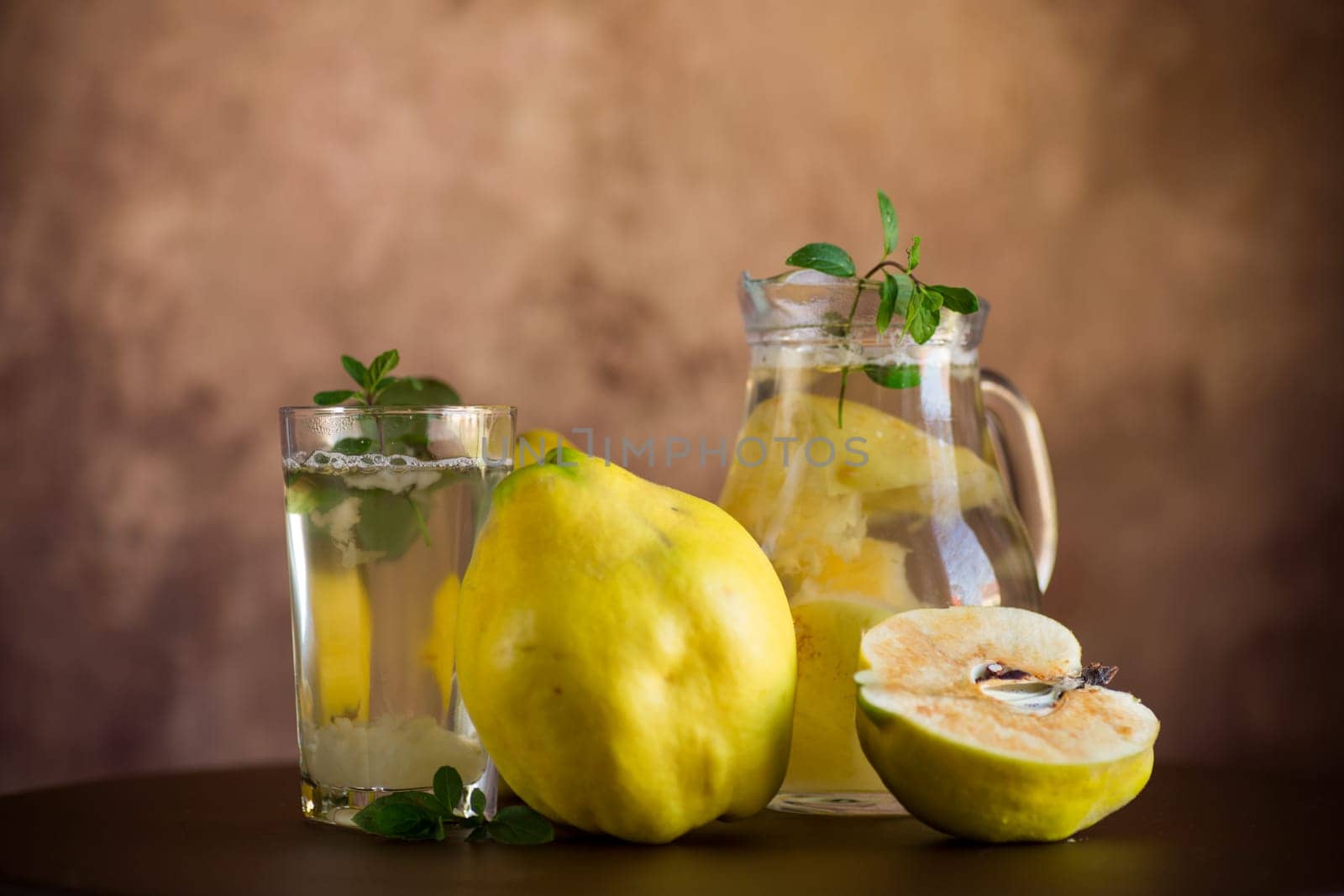 Prepared compote from ripe natural autumn quince, in a glass glass and decanter on a dark wooden table.