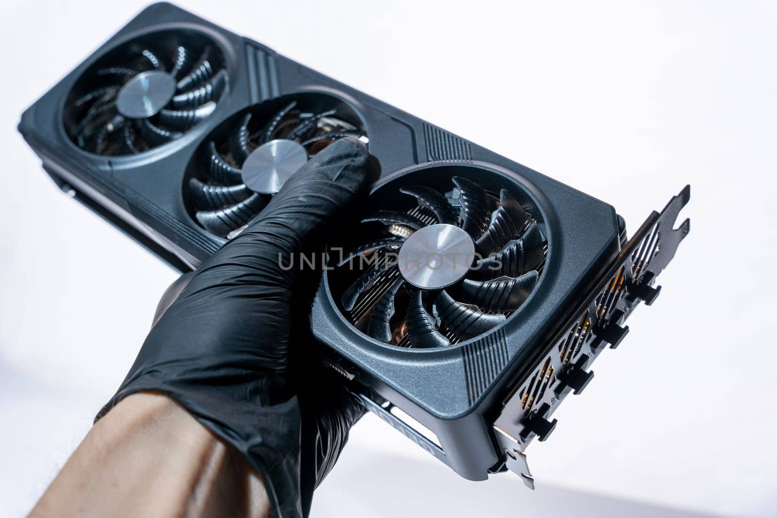 the hand of a computer technician holds a modern powerful video game card for a computer with three fans. the concept of PC hardware. Gaming video card