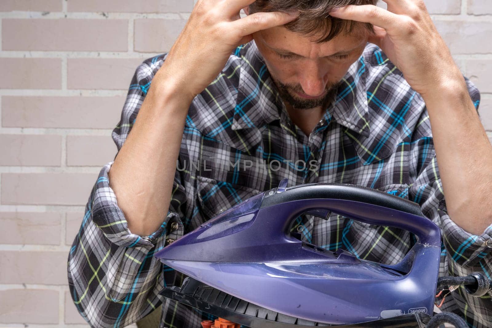 a mountain master repairs an electric iron. the repairman doesn't know how to fix it. Frustrated master. Disassembled electric iron.