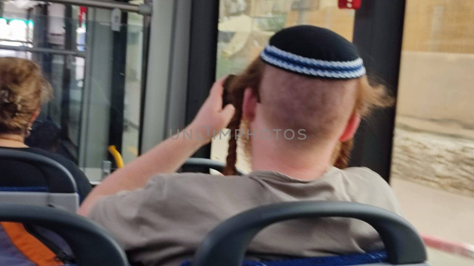red-haired Jewish guy in a kippah ri ftdes on a bus, sits with his back turned, people, young man. High quality photo