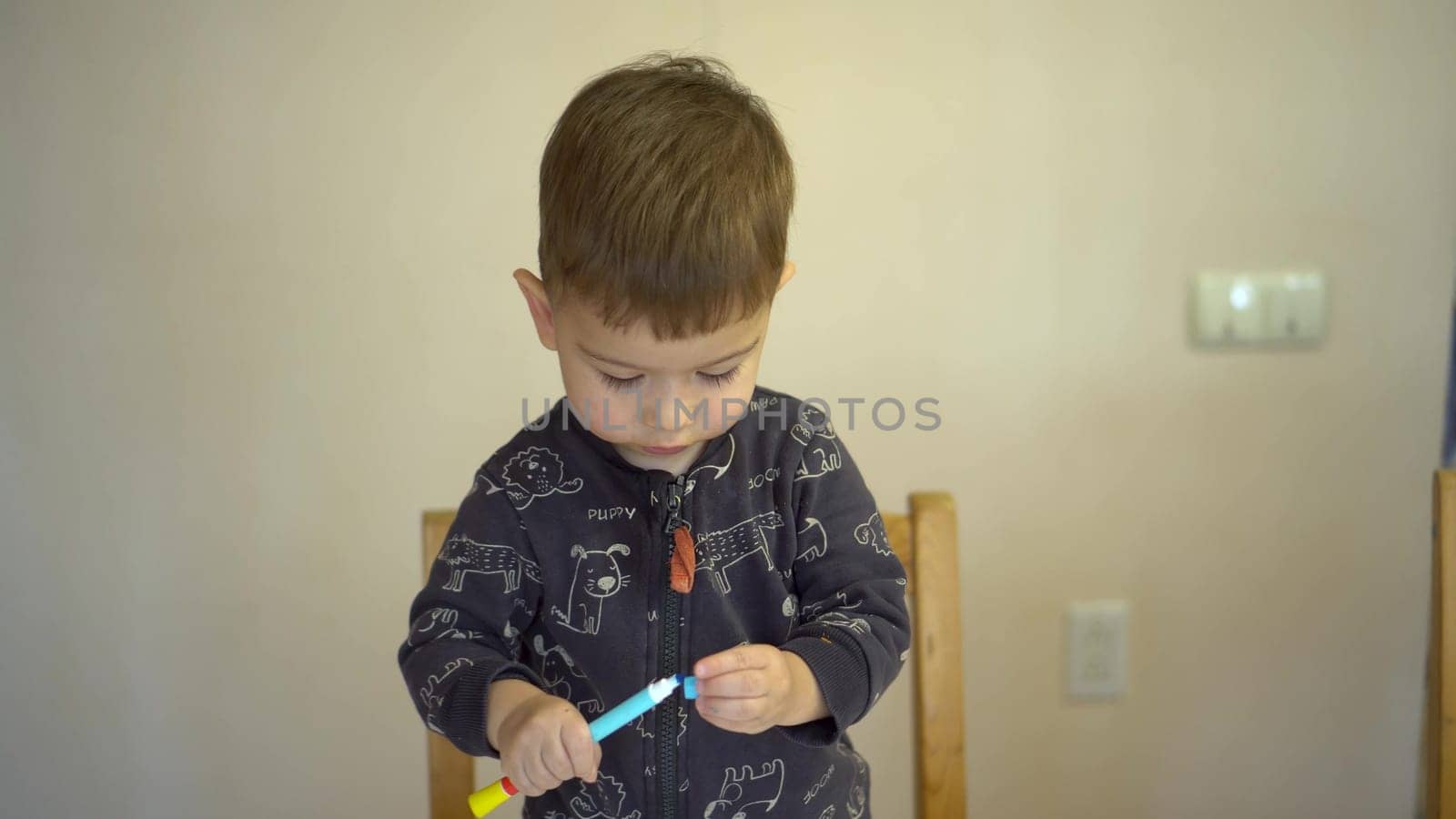 A little boy closes the cap of a felt-tip pen. Child with a felt-tip pen. 4k