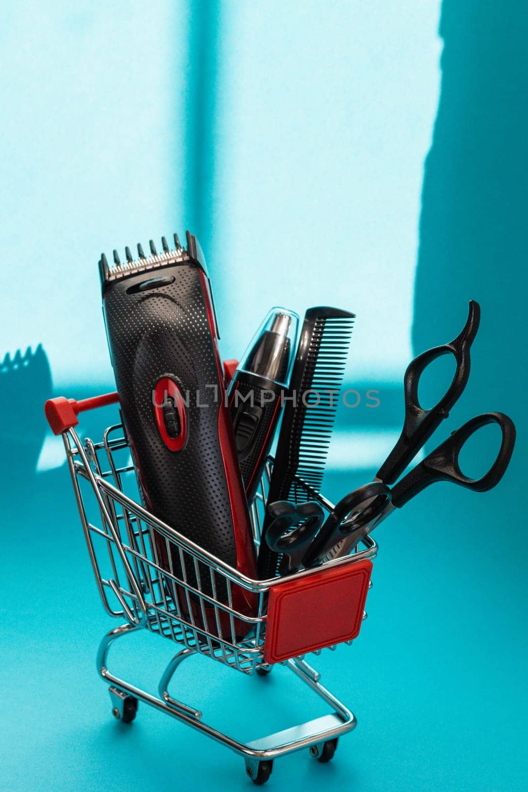 Hair clippers, two pairs of scissors and one comb lie in a mini basket on a blue background, close-up side view. The concept of hairdressing and shopping.
