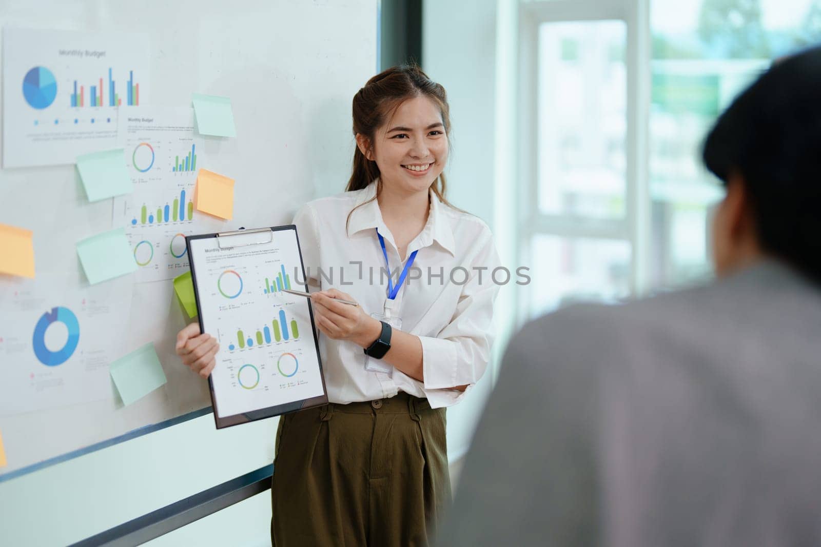 portrait of young asian business team presents business profits to colleagues at meeting, explaining business turn over on flipchart to coworkers in office with using tablet