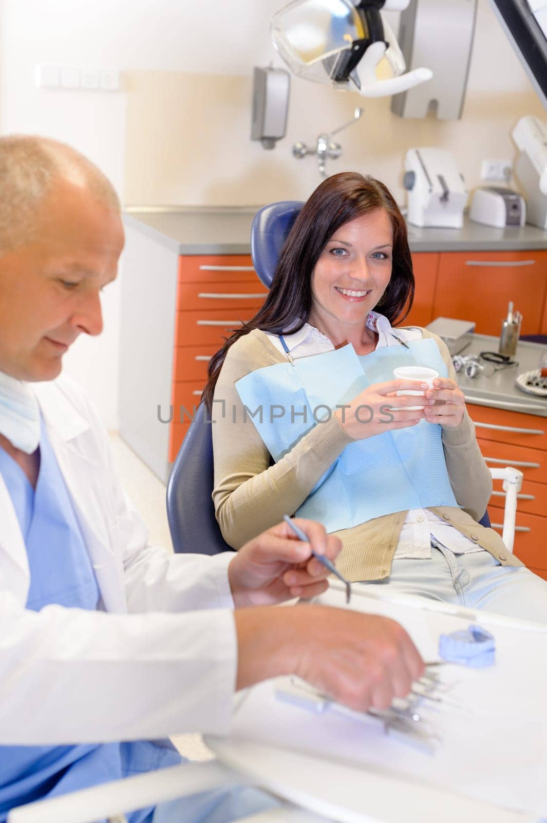 Smiling brunette woman sitting at dentist surgery chair dental clinic