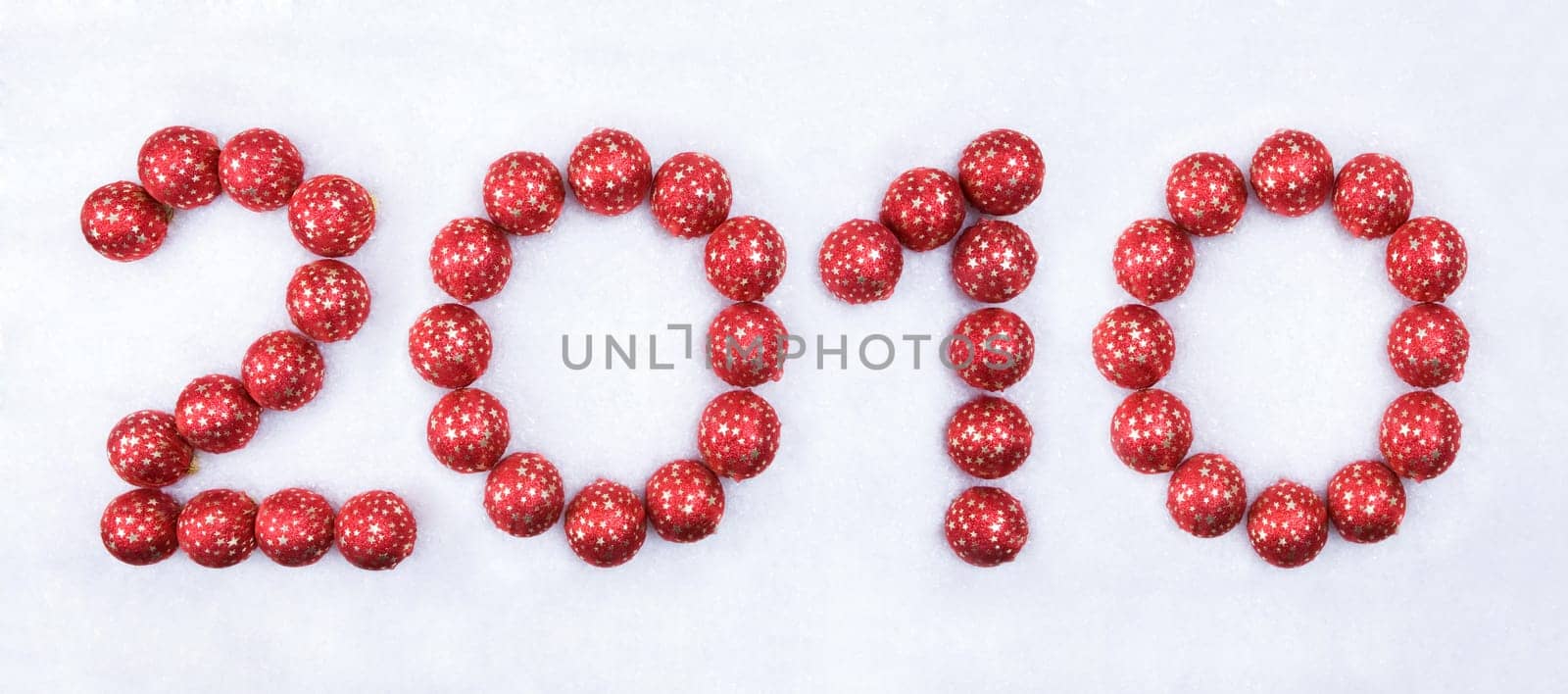 Image of 2010 number made up of red decorative toy balls on the snow