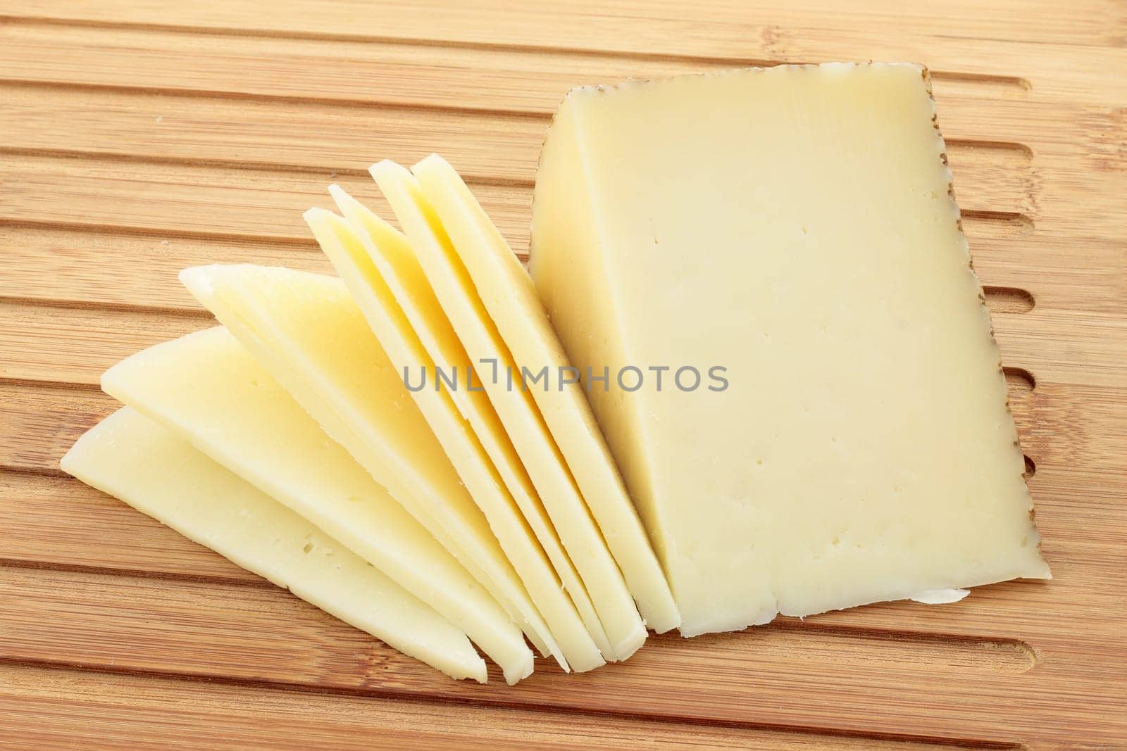 table of cut with wedge of cheese cut partially sliced