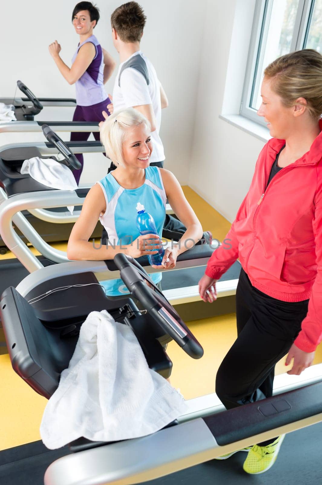 Young woman friends exercising in fitness center on treadmill machine