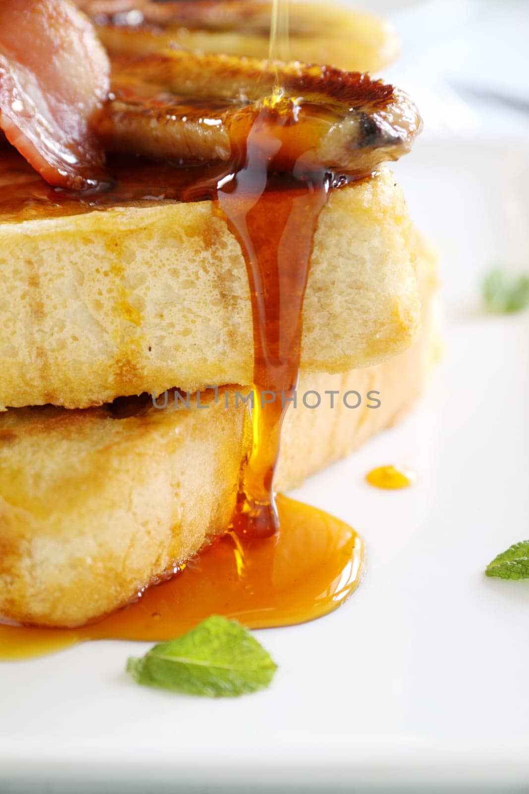 Maple syrup dripping down caramelized banana and french toast.