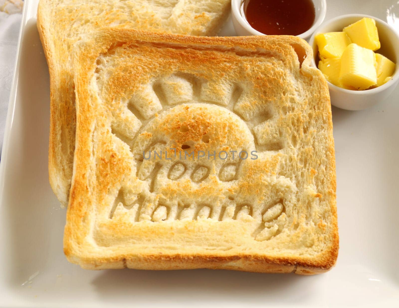 Slice of toast with Good Morning carved into it with butter and honey.