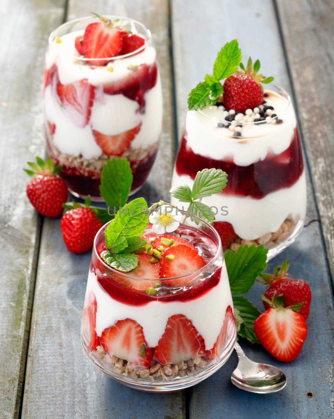 Assortment of creamy gourmet strawberry desserts layered in decorative patterns in individual glass containers