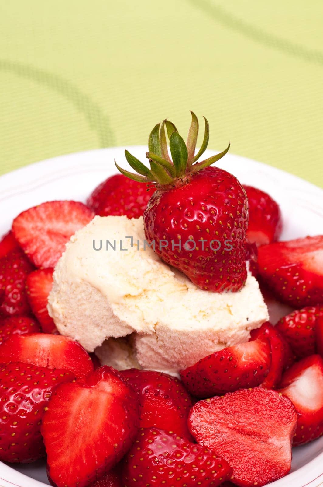 Red strawberries with vanilla ice cream in front of a green background