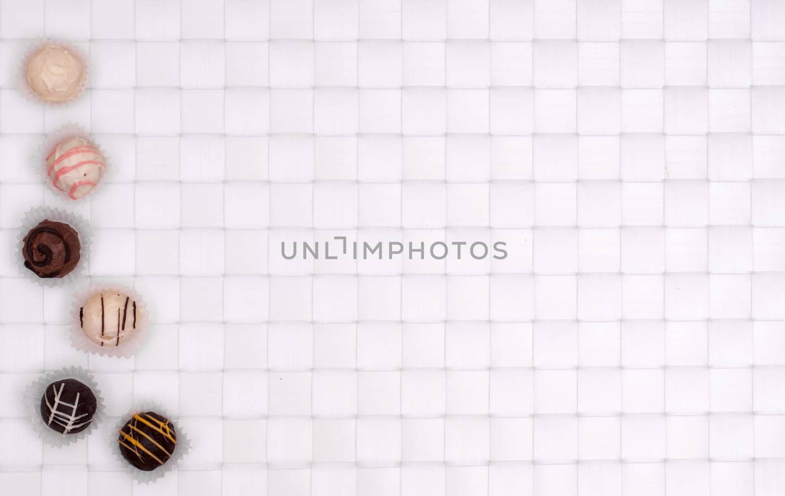 White and brown chocolates on white braided background