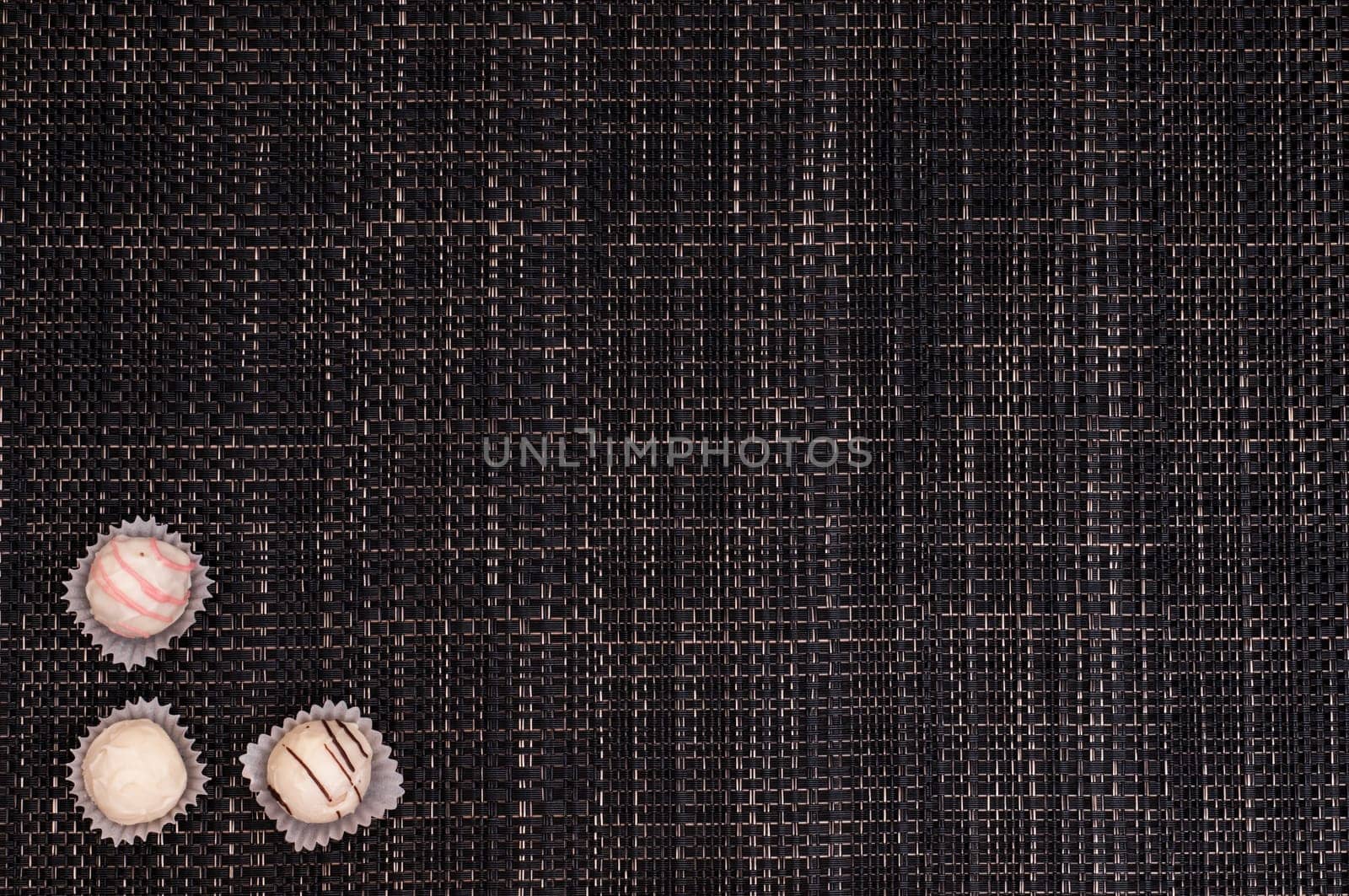 Dark braided background with white truffle chocolates