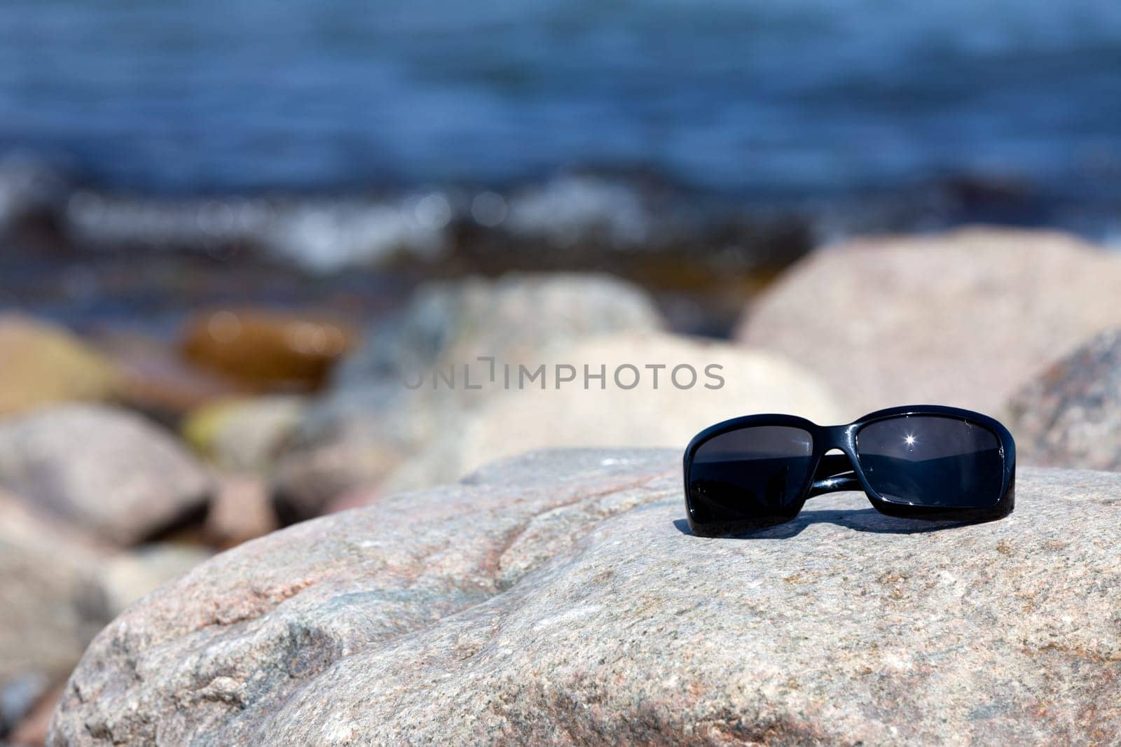 Modern sunglasses on a large rock