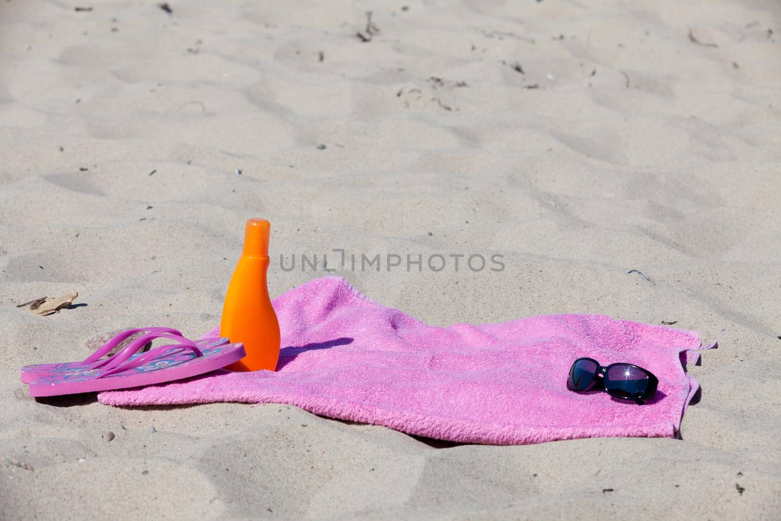 Bath towel and sunscreen on the sandy beach
