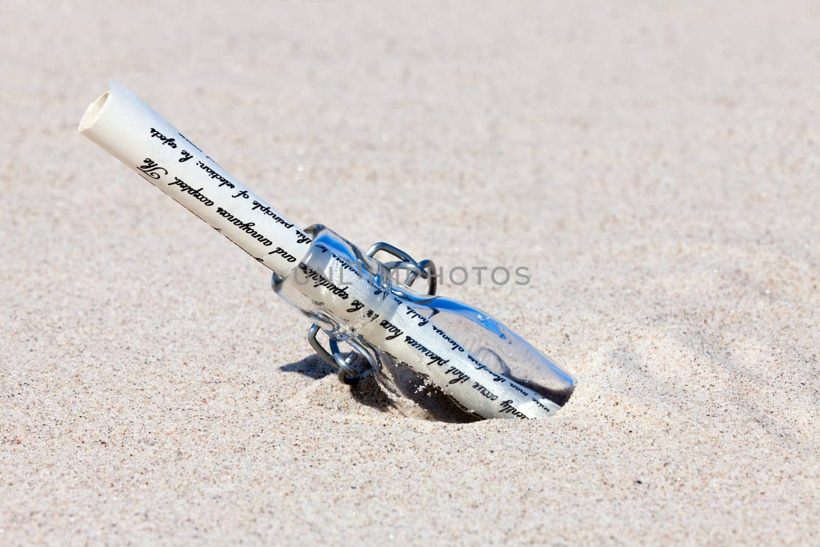 Message in a bottle with letter in the sand