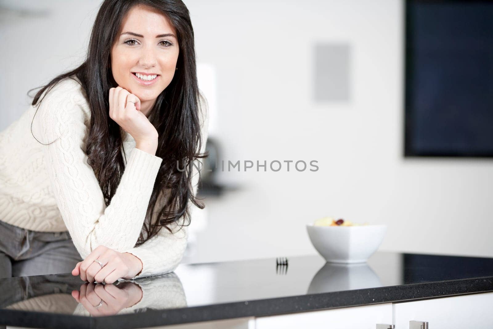 Young woman enyoying a bowl of fresh fruit in her kitchen