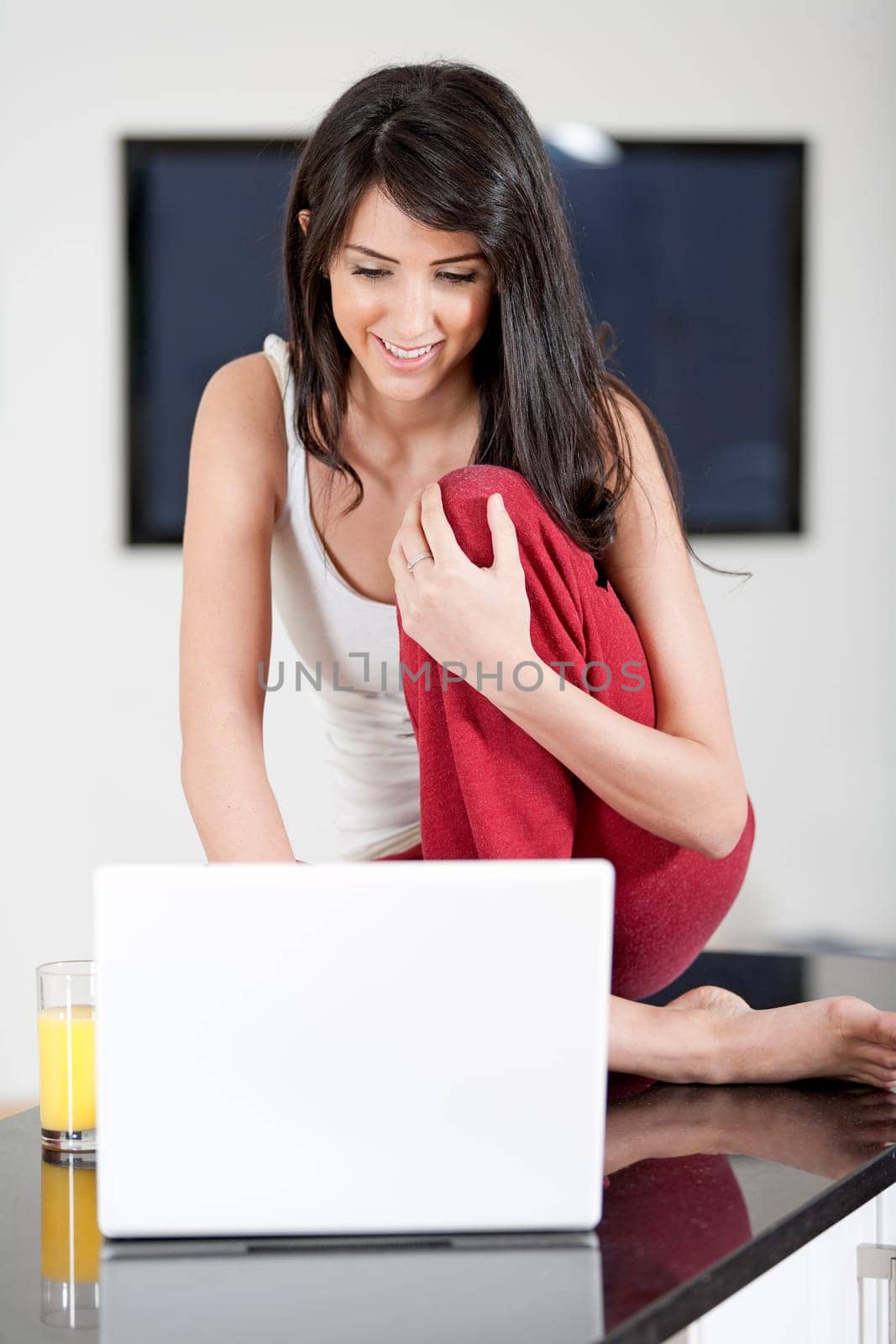 Young woman sat in kitchen on laptop