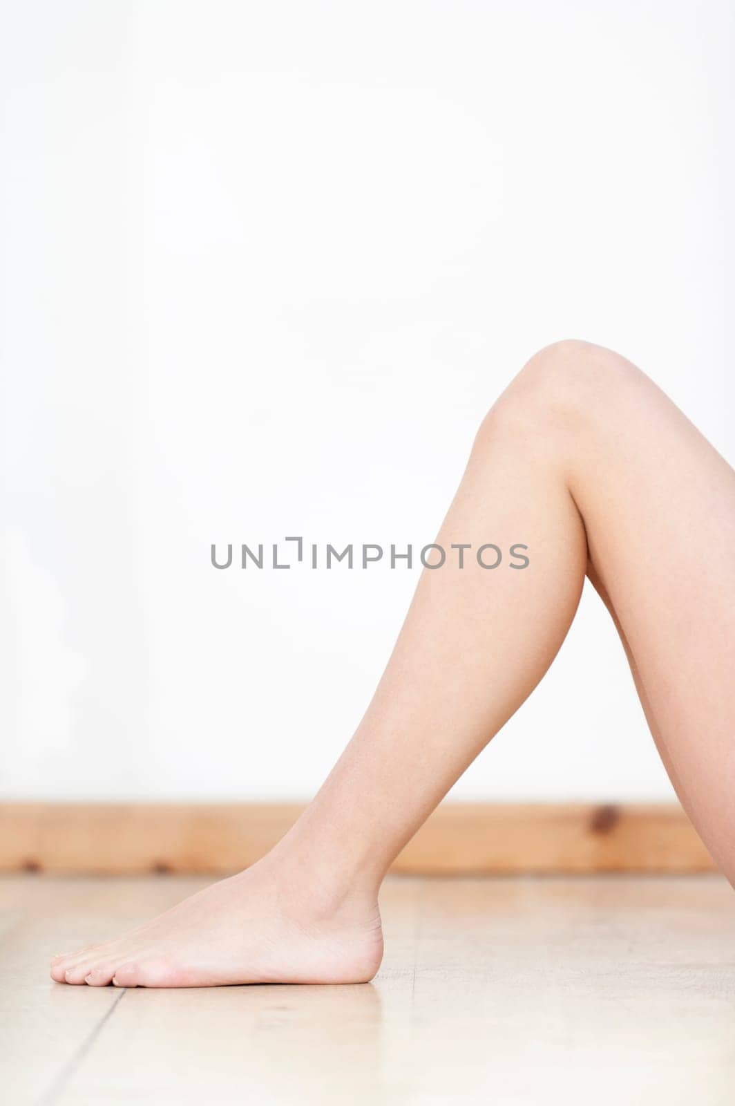 Womans legs on wooden floor against a white wall back drop.