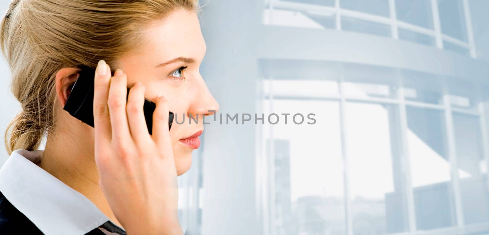 Profile of confident businesswomans face with her hand holding cellular phone isolated on the background of office building