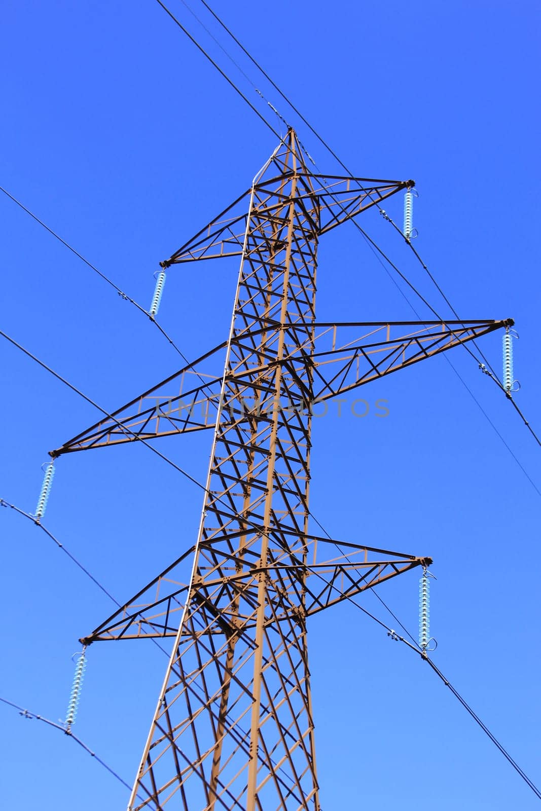 High voltage pylon in front of blue sky