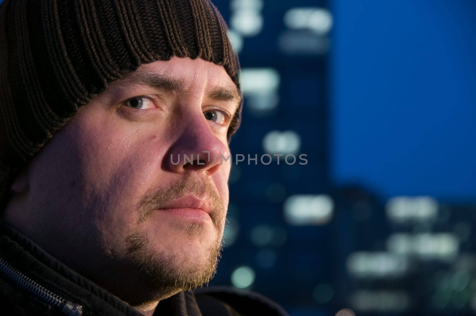 Head portrait of a middle-aged man wearing a scare hat and looking at the camera seriously against a blurred night background