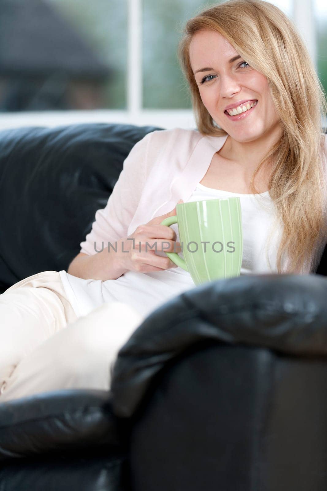 Young woman enjoying a hot drink at home on the sofa