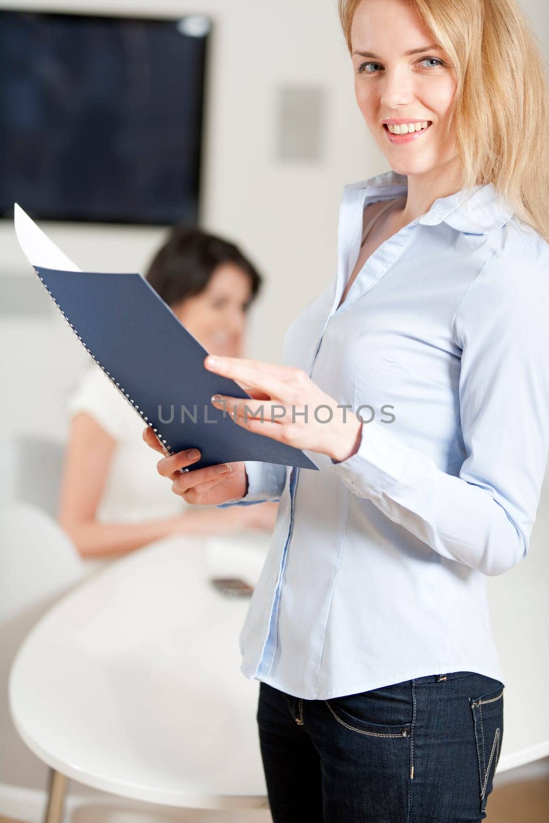 Two colleagues working in an office  one is in the background