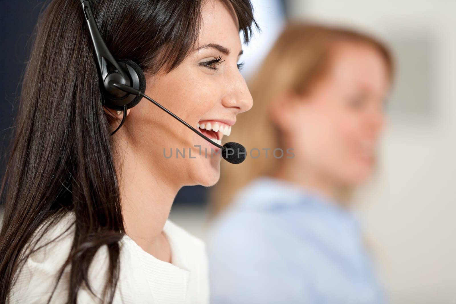 Two colleagues working in a busy call centre office.