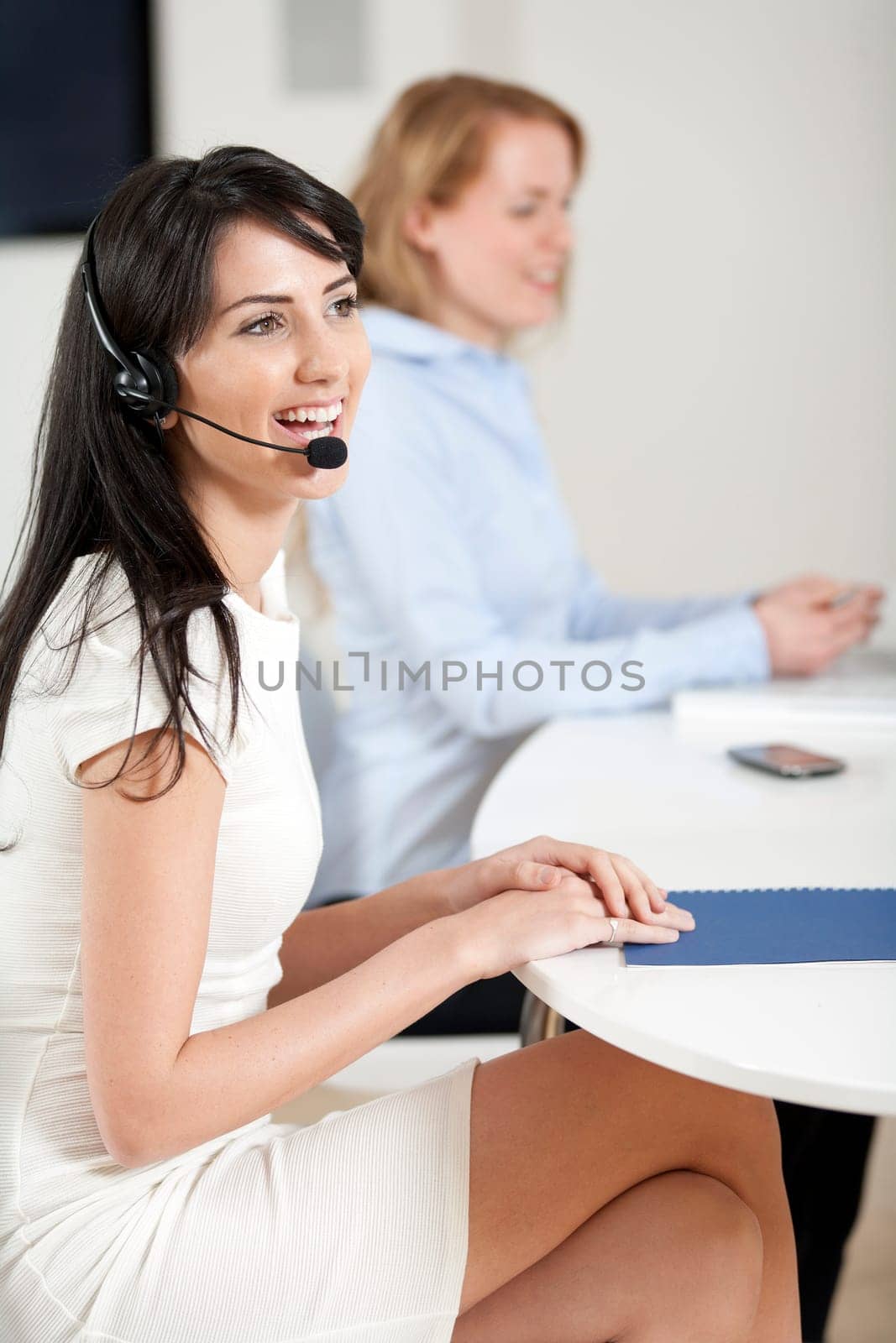 Two colleagues working in a busy call centre office.