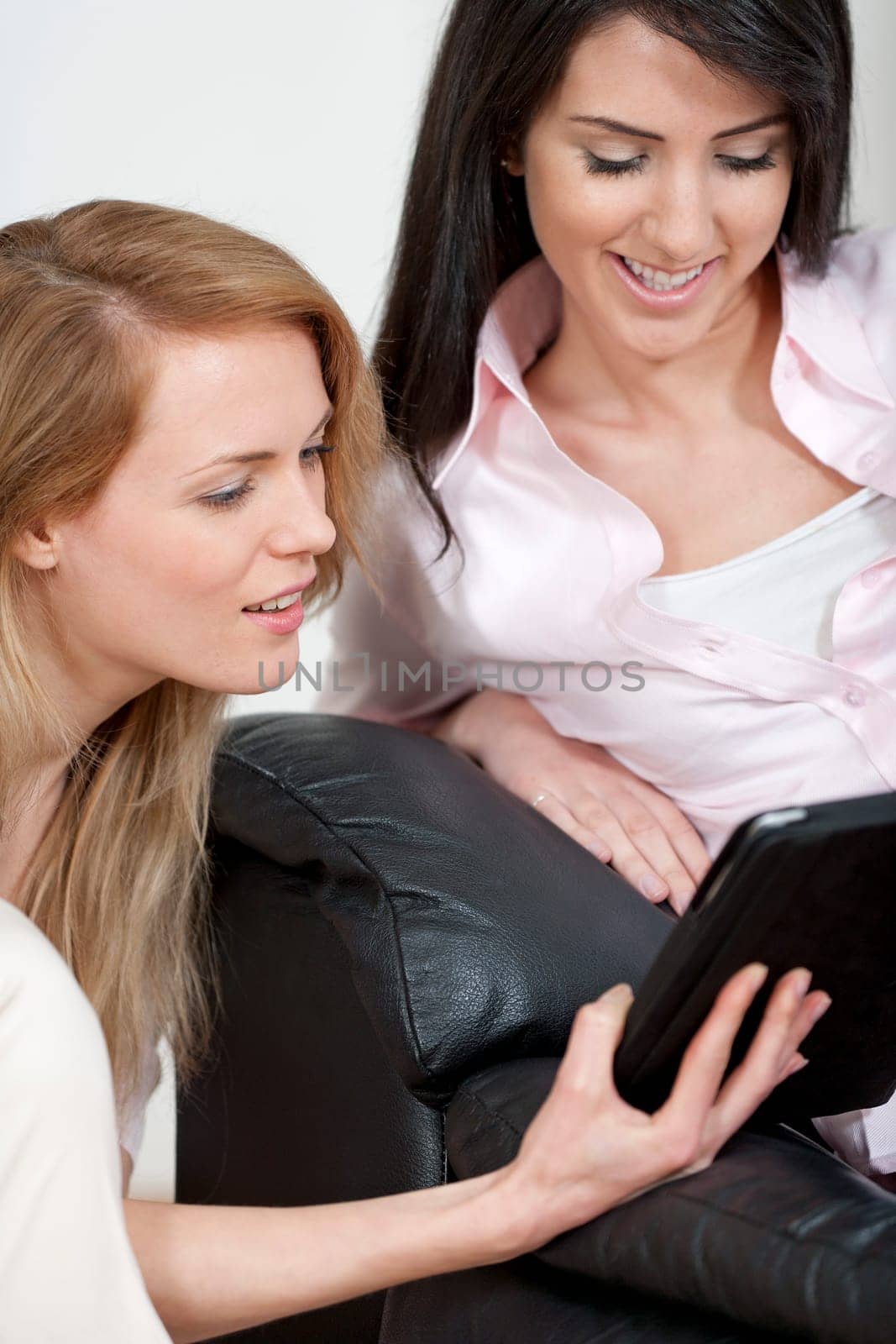 Two woman in their sitting room chatting and having fun on an electronic tablet