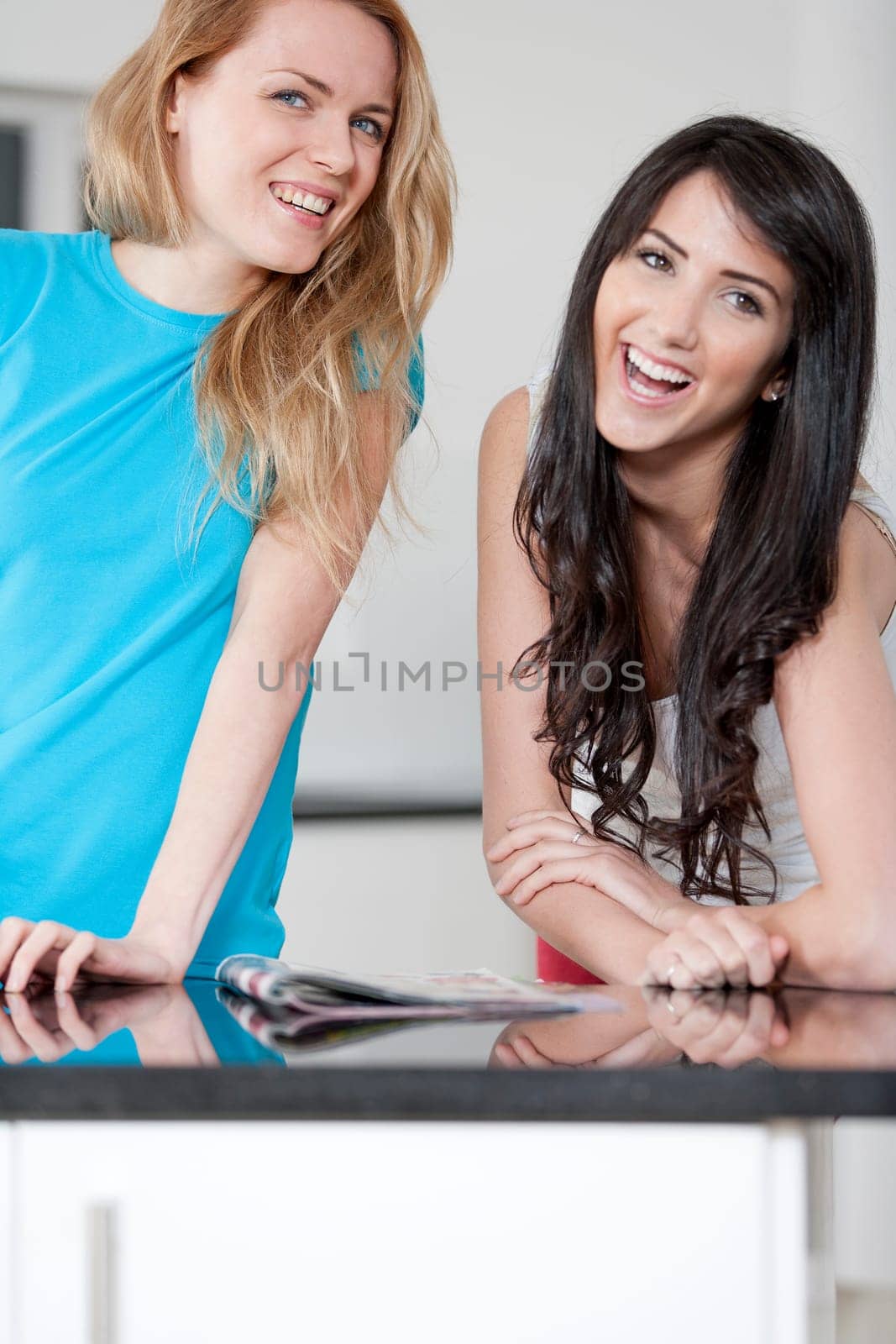 Two young woman chatting and sharing a magazine