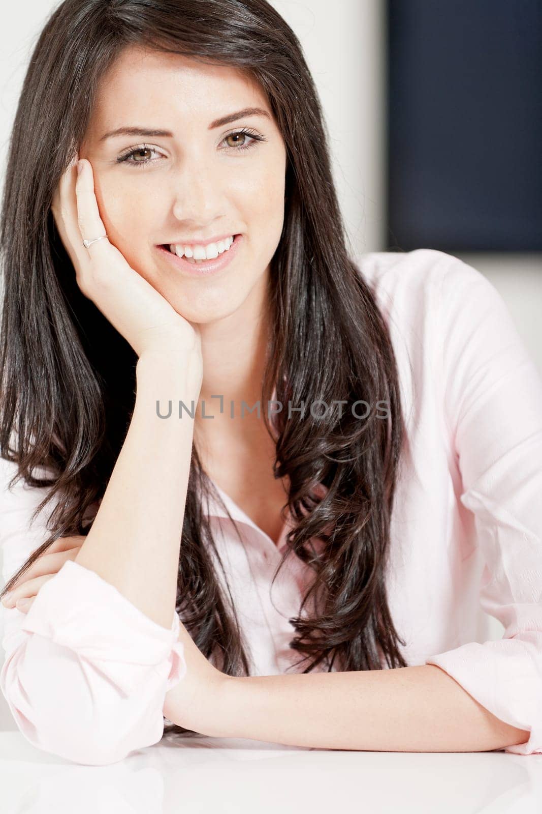 Young woman in pink shirt sitting at dining table at home