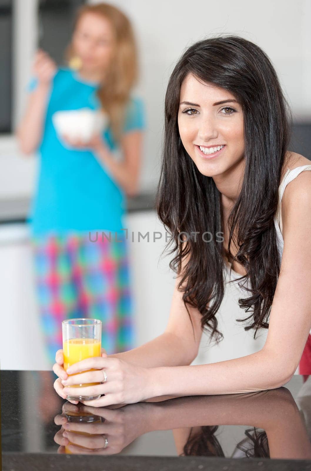 Two young woman having juice and breakfast at home