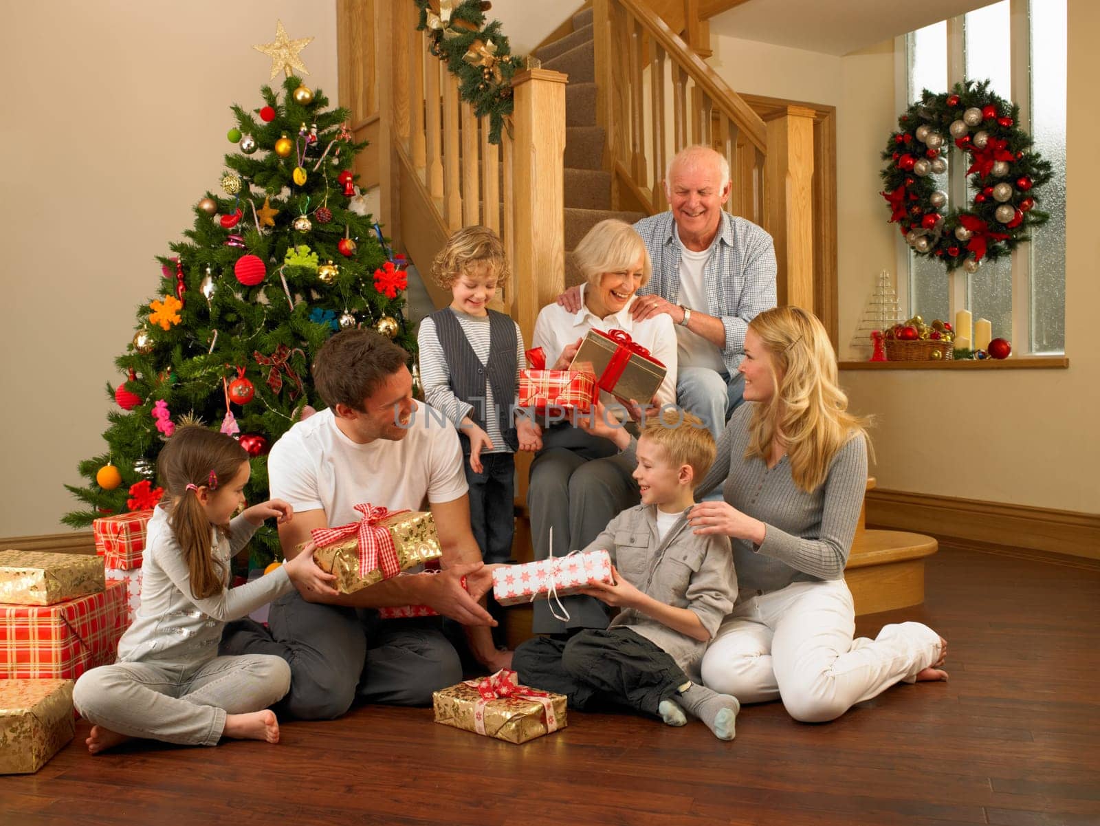 Family exchanging gifts in front of Christmas tree