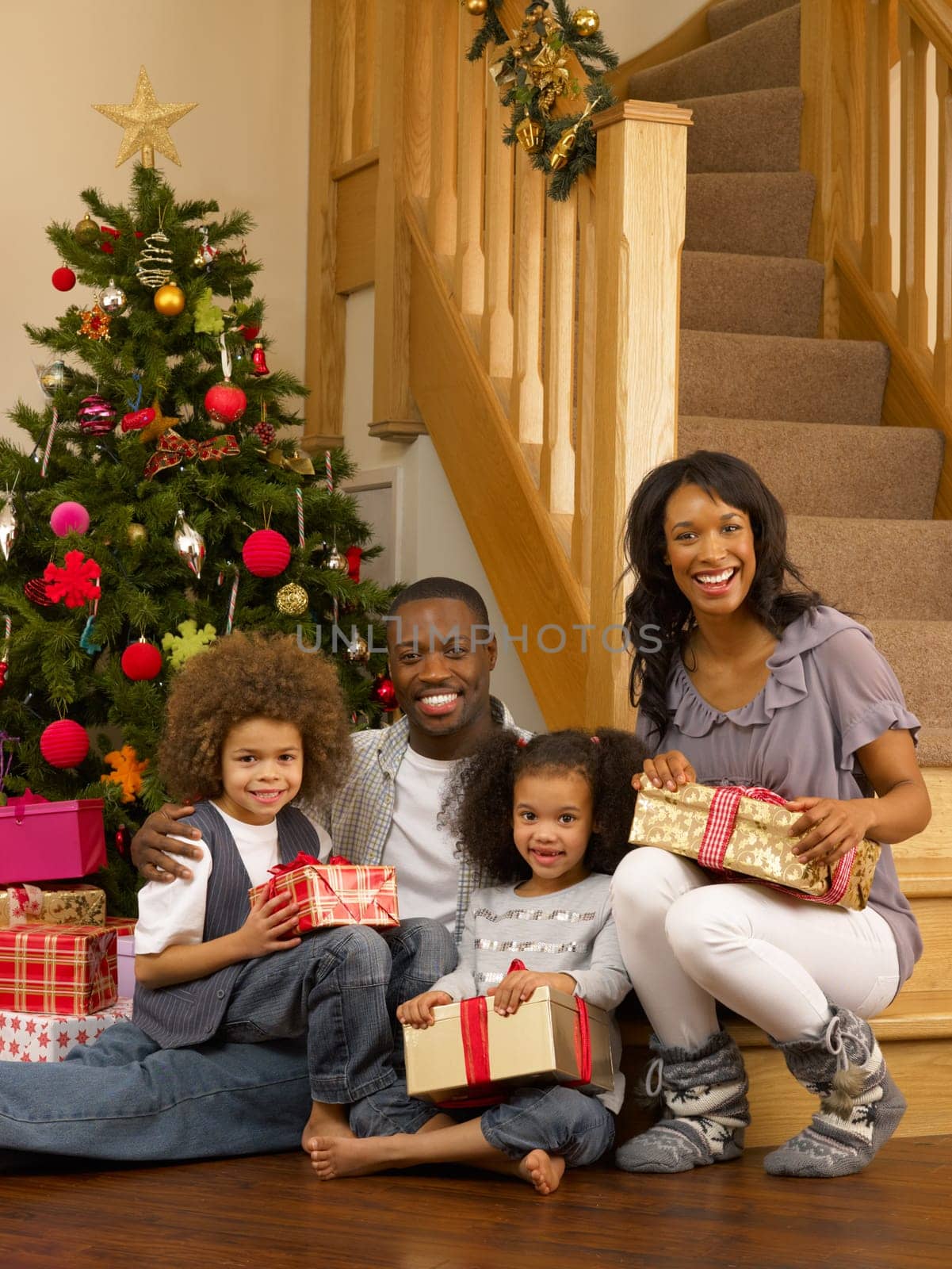 Young African American family with Christmas tree and gifts