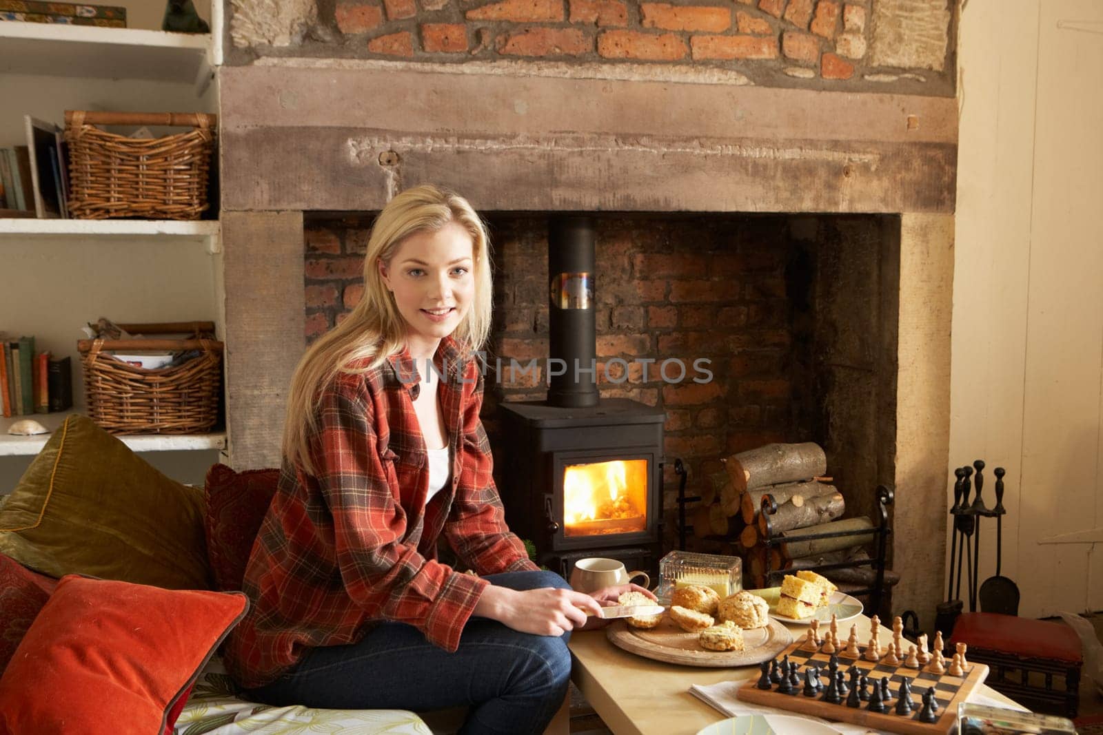 Young woman having tea by fire