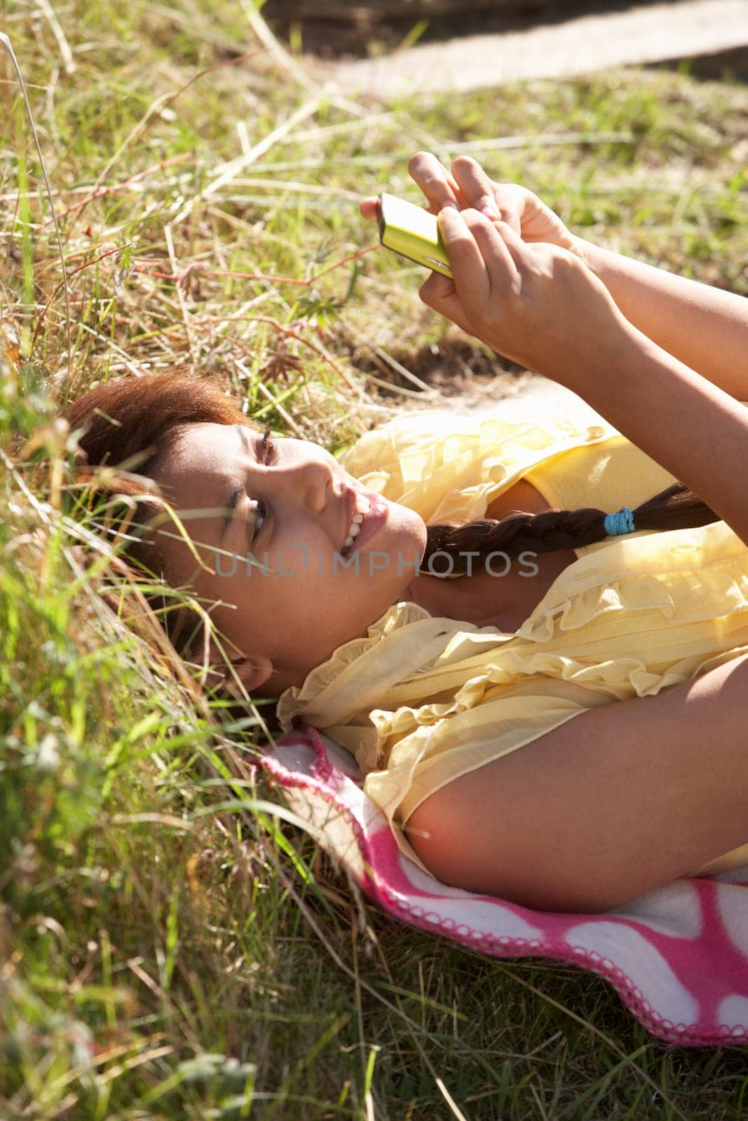 Teenage girl lying on grass with phone